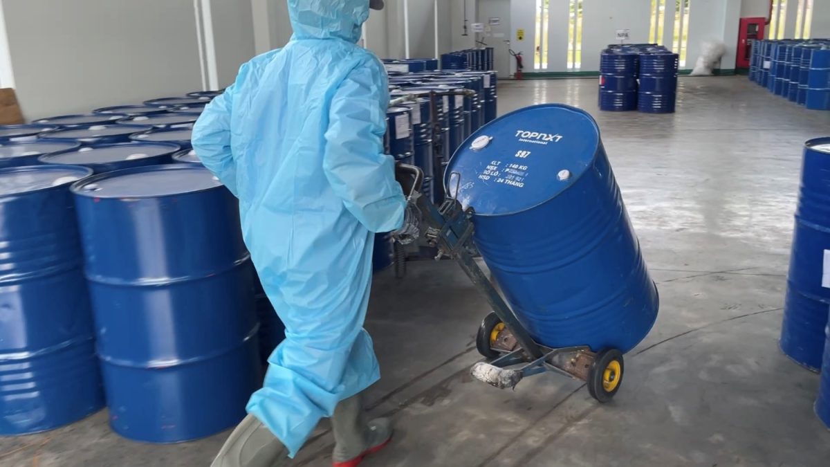 Nhân viên mặc đồ bảo hộ chuyên dụng di chuyển các thùng phuy hóa chất ra khỏi khu vực nguy hiểm.